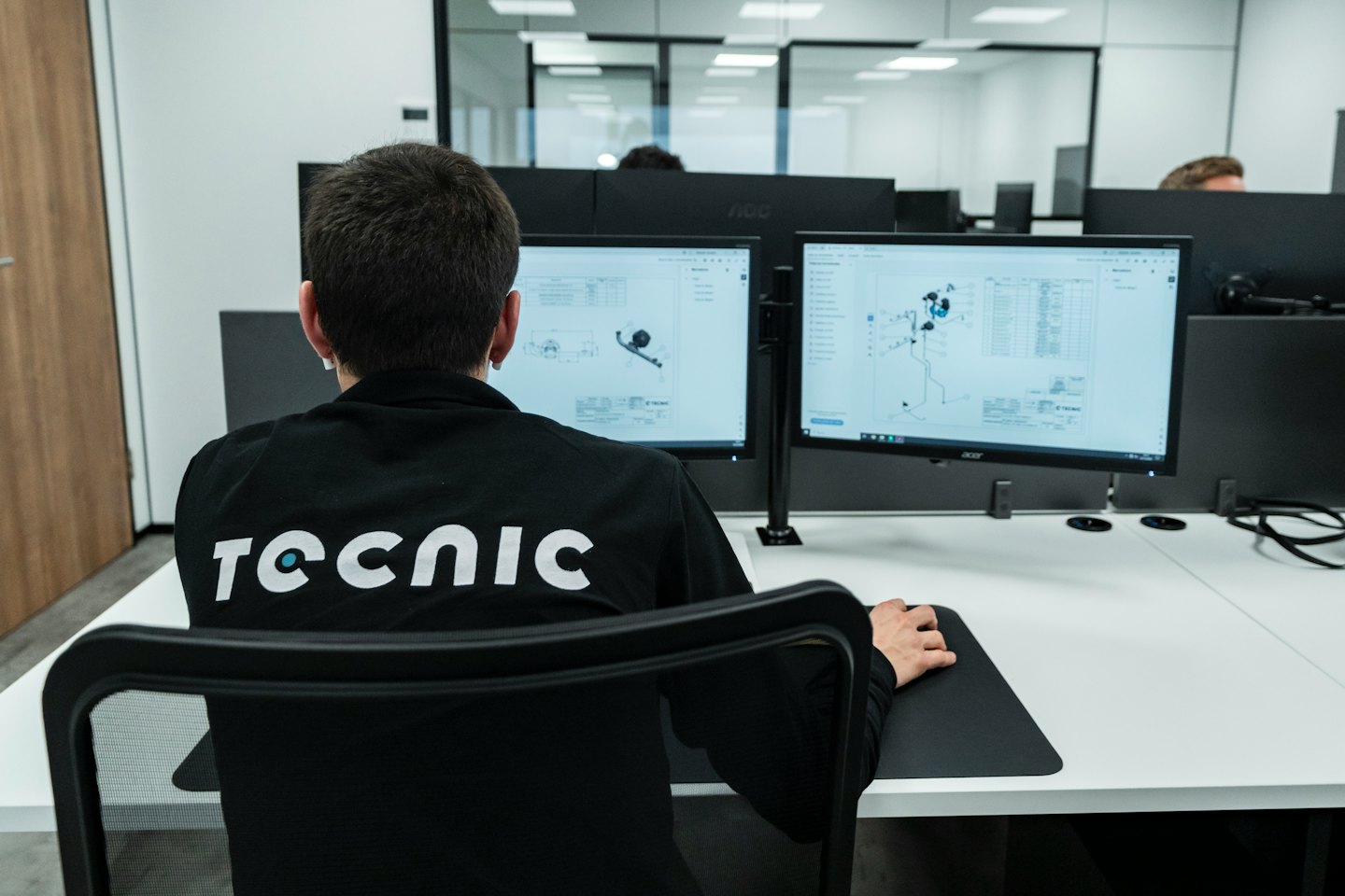 Professionista al lavoro su software CAD con una postazione a doppio monitor.