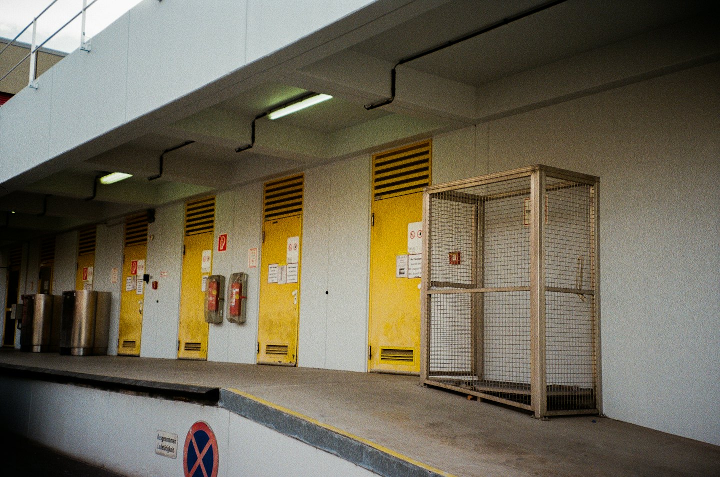 Cinque porte industriali gialle per carico con gabbia metallica.
